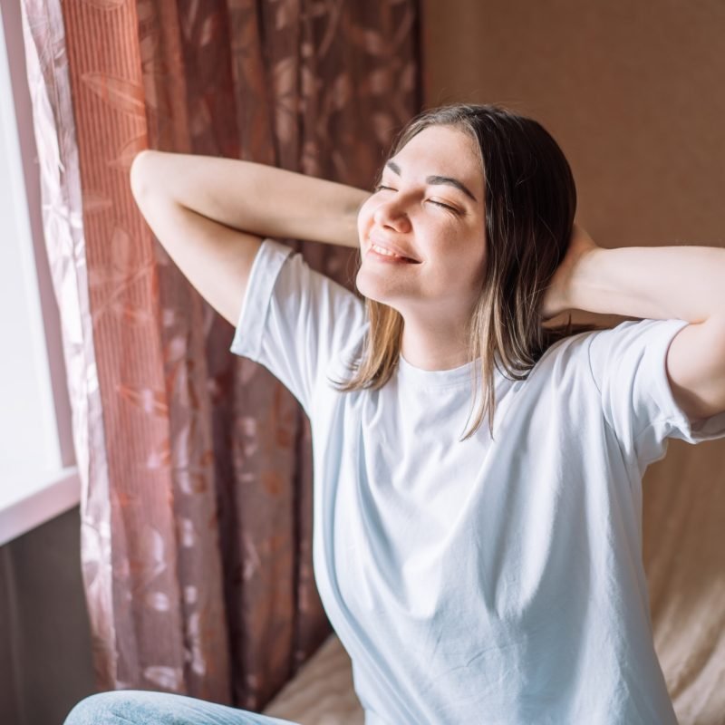 Happy lady in white t-shirt sitting on bed